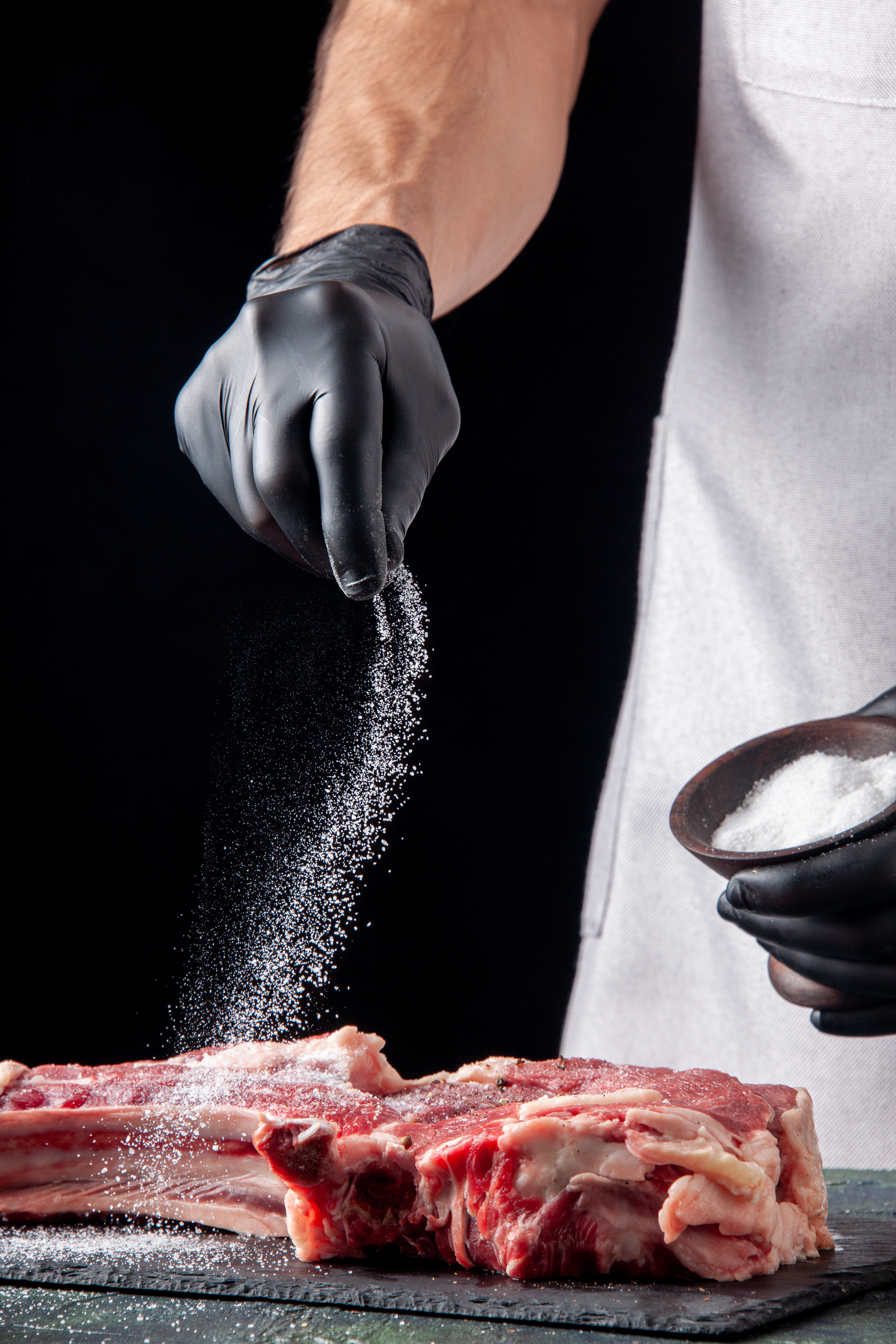 front-view-male-butcher-salting-meat-dark-surface